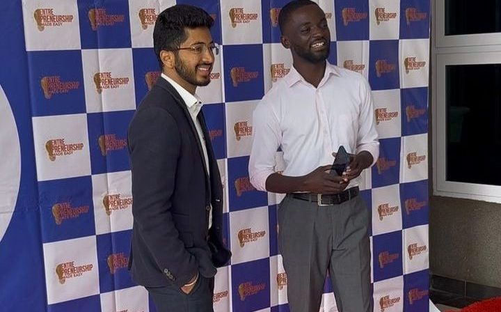 Two men in smart clothes standing in front of the event backdrop at the EME Summit 2025