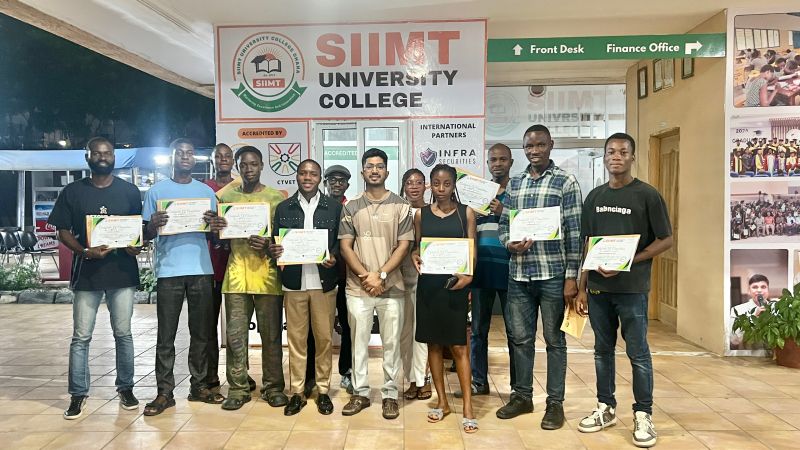 A group of participants holding certificates in front of the SIIMT University College reception
