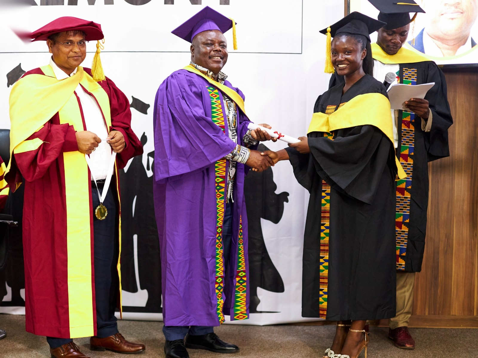 A graduate shaking hands with officials in academic gowns on stage at the SIIMT Graduation 2024