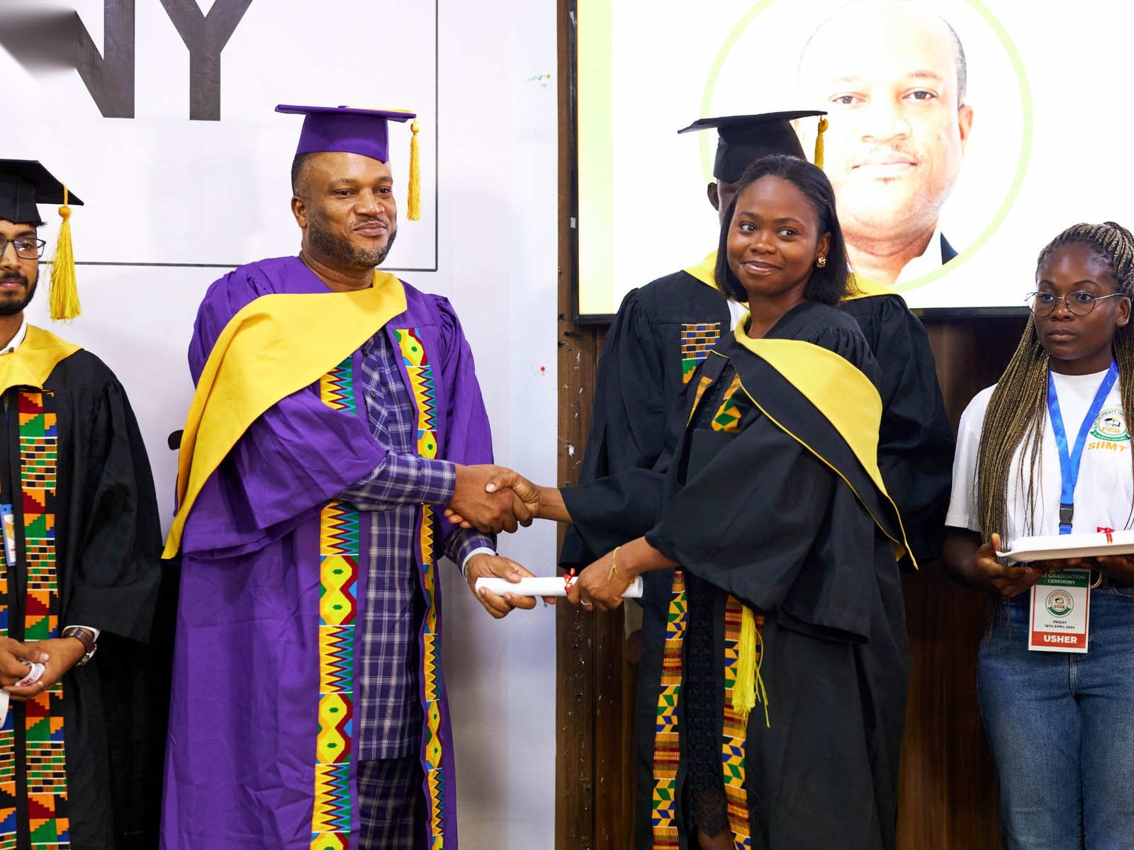 A graduate shaking hands with an official in a purple gown at the SIIMT Graduation 2024