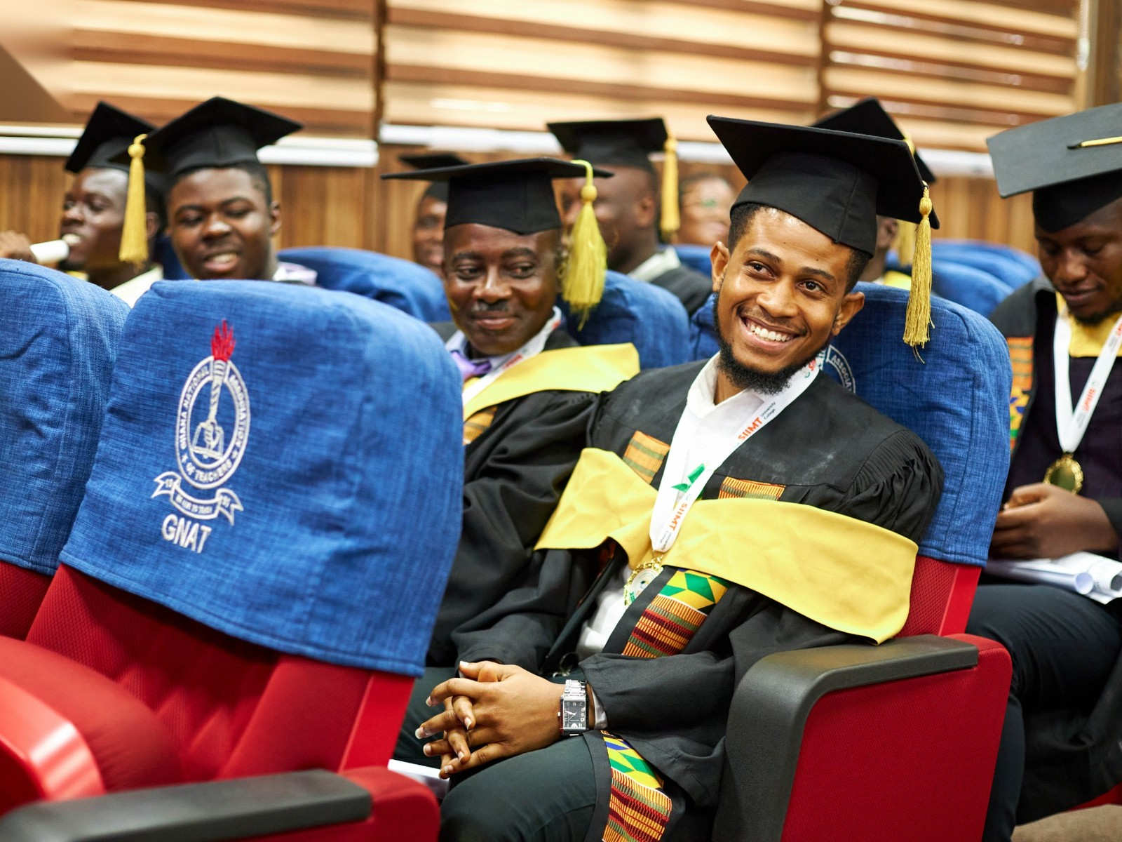 Smiling graduates in caps and gowns seated in the hall at the SIIMT Graduation 2024